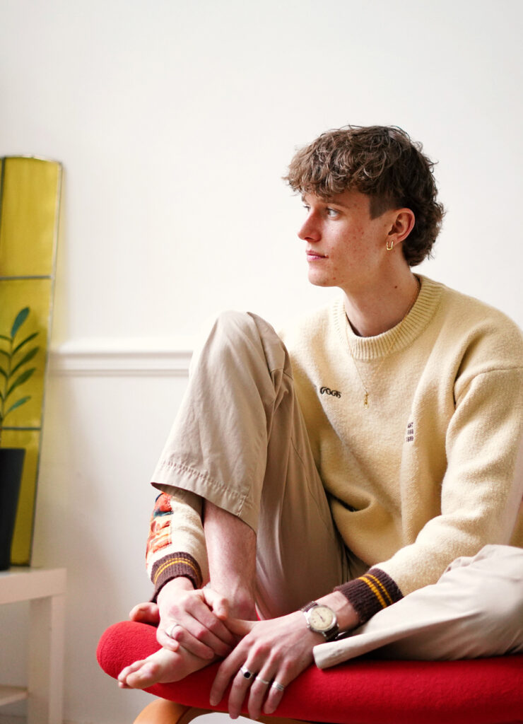 Etienne Yvelin sitting on a red chair looking away with a peaceful expression.